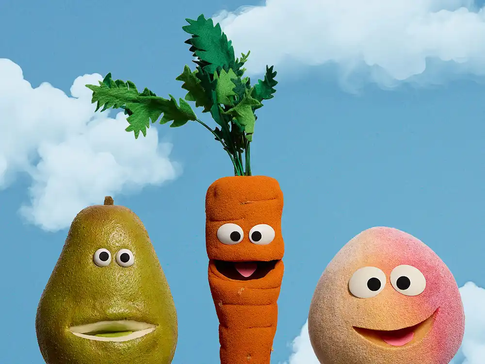 Pear, carrot, and peach puppets smile against a cloudy blue sky, from Compleat x Elmo's What Is Better Than How