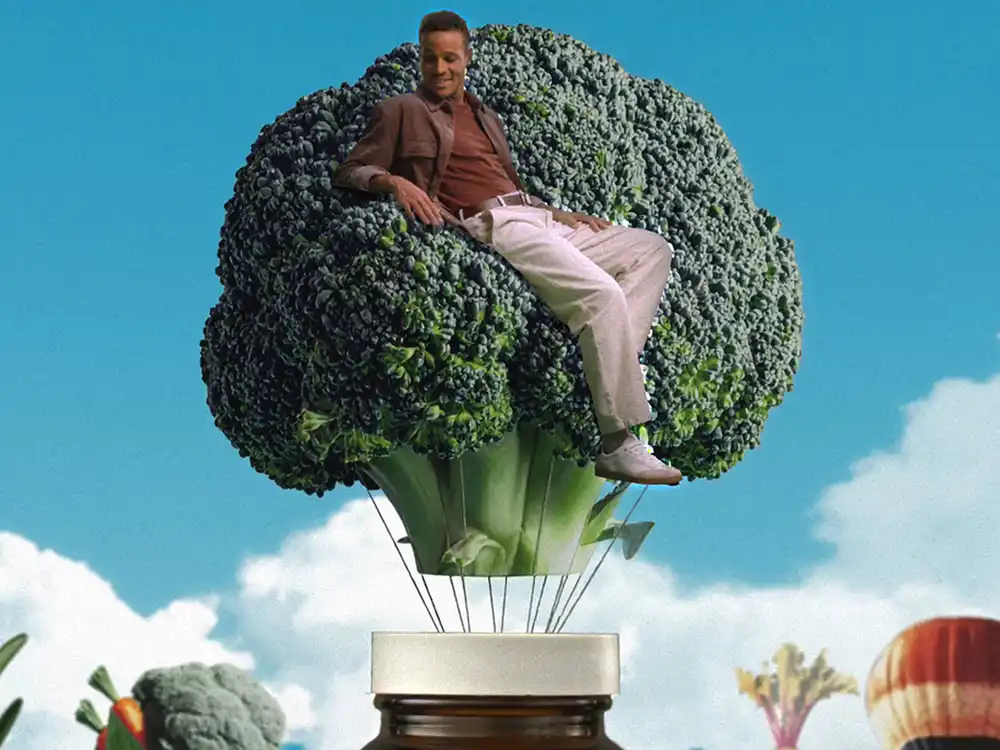 A man sits in a broccoli floret balloon lifting off a supplement bottle, from Garden of Life's Formulas for Feeling Alive