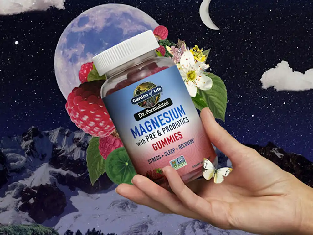 A hand holds Garden of Life Magnesium gummies under a moonlit sky of raspberries, from Formulas for Feeling Alive