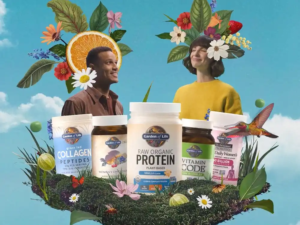 Two people smile behind a row of Garden of Life tubs on a mossy mound, from Formulas for Feeling Alive