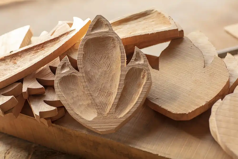 Carved wooden dinosaur-footprint trays stacked among unfinished wood pieces on a workbench