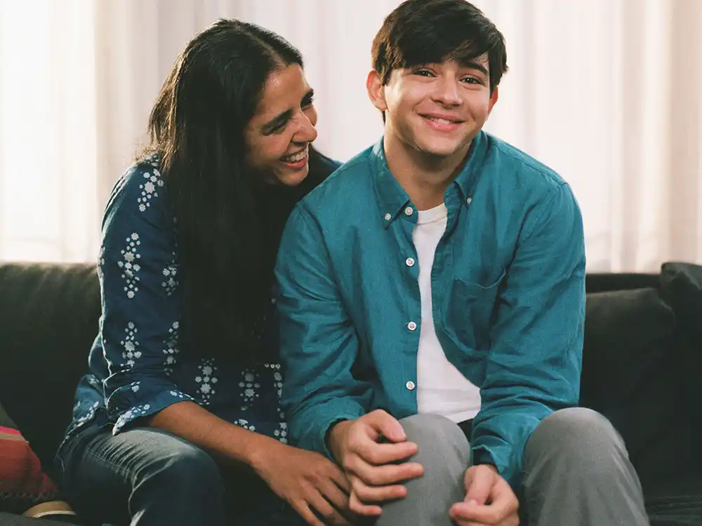 Avni Gupta-Kagan and her son Sonu sit smiling on a sofa, from Lambda Legal's All Rise campaign
