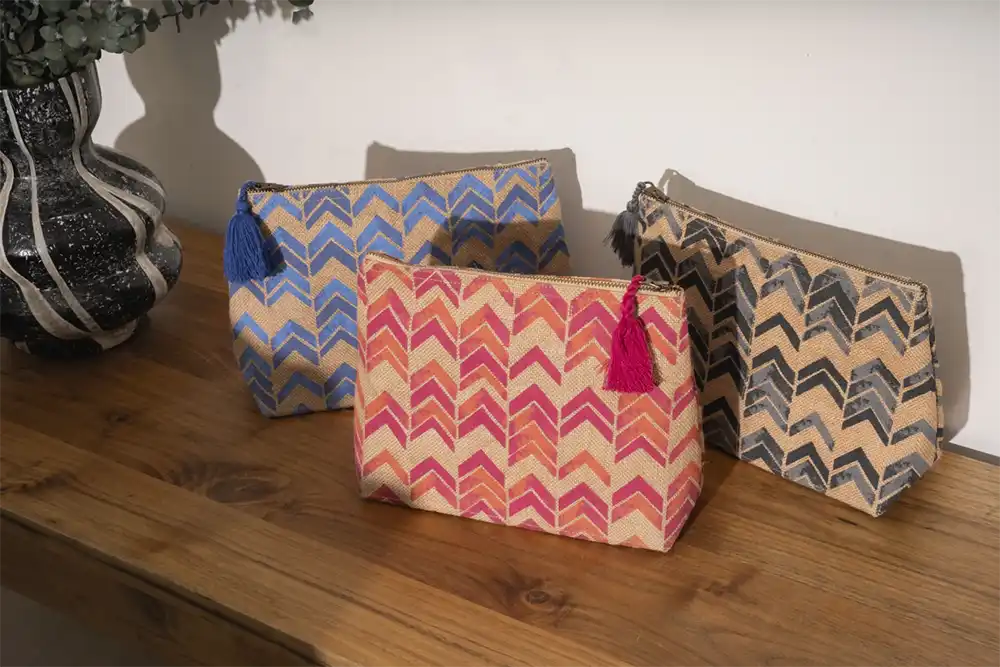 Three chevron-patterned pouches with tassels on a wood table, from Neiman Marcus Gift with Purpose in Graphic Design USA