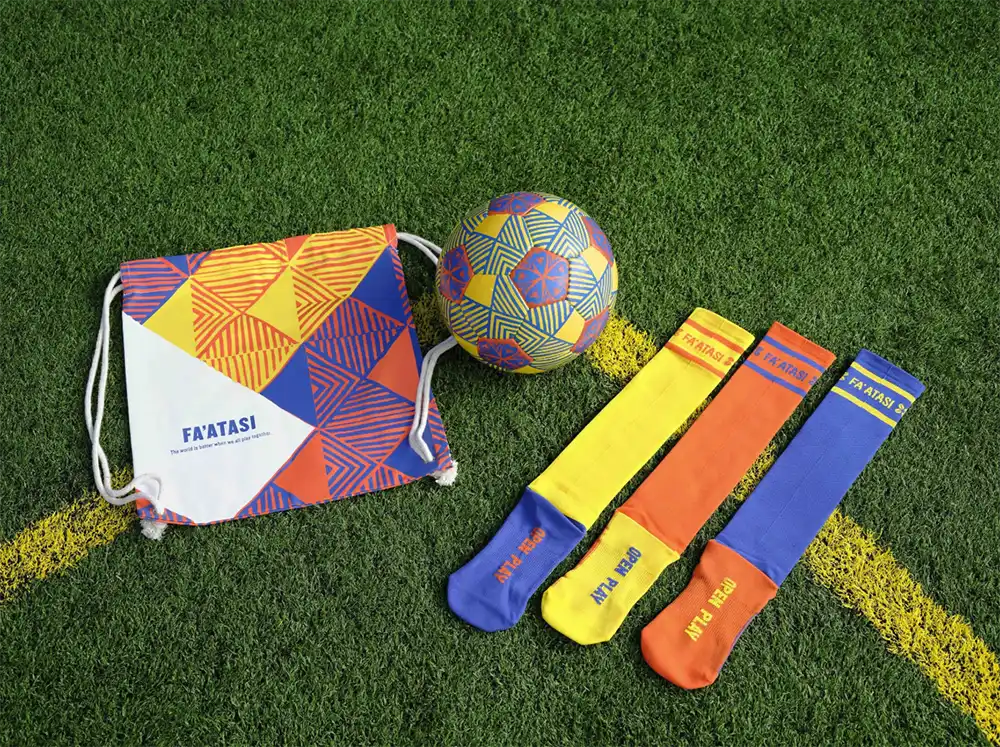 Fa'atasi drawstring bag, patterned soccer ball, and trio of socks on turf from the Next Goal Wins capsule, Shorty Impact Awards
